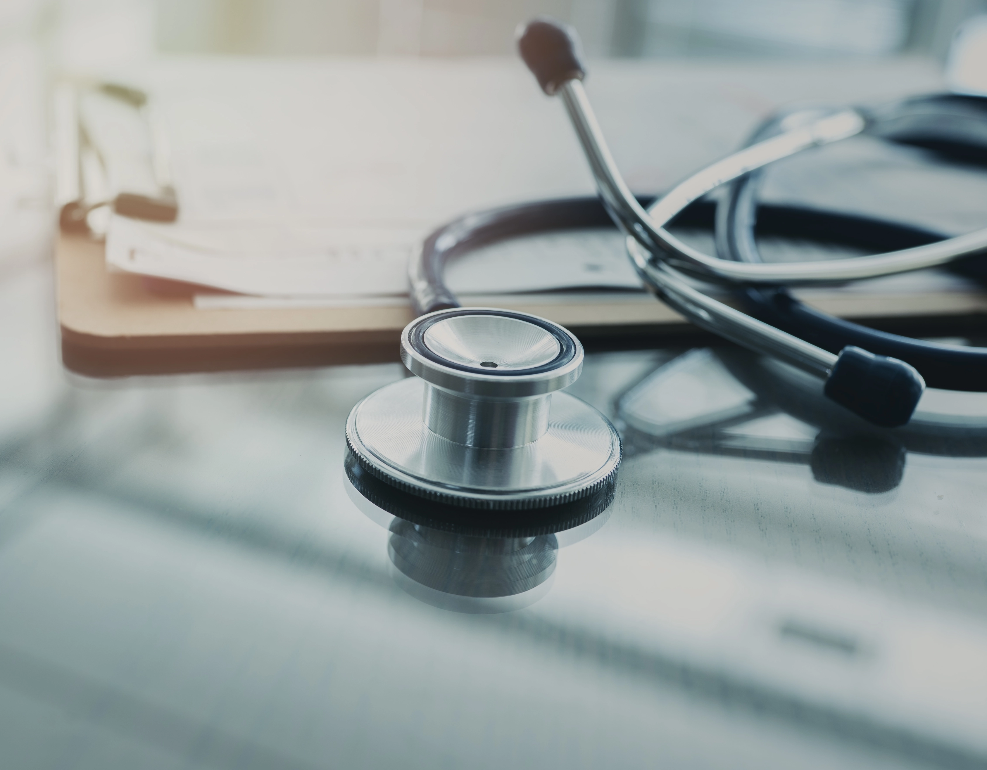 Stethoscope resting on a desk beside a clipboard
